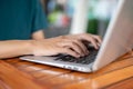 A man working on his laptop, typing on the laptop keyboard, sitting at an outdoor table of a cafe Royalty Free Stock Photo