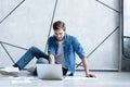 Man working at home. Handsome young man sitting on the floor and examining document while laptop and documents laying Royalty Free Stock Photo