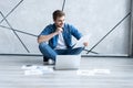 Man working at home. Handsome young man sitting on the floor and examining document while laptop and documents laying Royalty Free Stock Photo