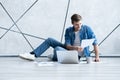 Man working at home. Handsome young man sitting on the floor and examining document while laptop and documents laying Royalty Free Stock Photo