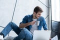 Man working at home. Handsome young man sitting on the floor and examining document while laptop and documents laying Royalty Free Stock Photo