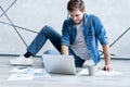 Man working at home. Handsome young man sitting on the floor and examining document while laptop and documents laying Royalty Free Stock Photo