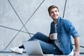 Man working at home. Handsome young man sitting on the floor and examining document while laptop and documents laying Royalty Free Stock Photo