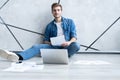 Man working at home. Handsome young man sitting on the floor and examining document while laptop and documents laying Royalty Free Stock Photo