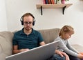 Man working from home on his computer while his daughter is playing.