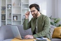 Man working from home on laptop with headset, smiling confidently Royalty Free Stock Photo
