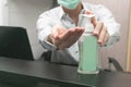 Man working from home wearing protective mask. Cleaning her hands with sanitizer gel Royalty Free Stock Photo