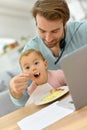 Man working on laptop and feeding baby Royalty Free Stock Photo