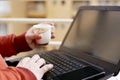 Man is working on the laptop with holding tea cup in hand Royalty Free Stock Photo