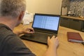Man working on laptop on the kitchen counter top with an excel sheet on computer screen showing bank loan amortization table. Royalty Free Stock Photo