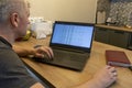 Man working on laptop on the kitchen counter top with an excel sheet on computer screen showing bank loan amortization table. Royalty Free Stock Photo