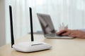 Man working with laptop in office, focus on router. Wireless internet communication Royalty Free Stock Photo