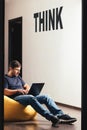 Man working on laptop and sitting on bean bag Royalty Free Stock Photo