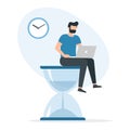 A man working on a laptop sitting on big hourglass. Time management and deadline concept Royalty Free Stock Photo