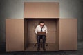 Man working on laptop sitting on chair inside carton box