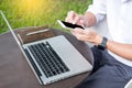 Man working on modern laptop sitting outside natural hardwood desk with green flora background sunlight day outdoor, everywhere Royalty Free Stock Photo