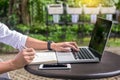 Man working on modern laptop sitting outside natural hardwood desk with green flora background sunlight day outdoor, everywhere Royalty Free Stock Photo