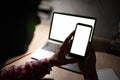 Man working at night using laptop and texting mobile. Computer screen, cell phone blank mockup. White background for Royalty Free Stock Photo