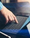 Man working at office. Closeup view of male finger touching electronic tablet keyboard-dock station. Vertical, sunlight