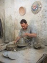 Man working on potter's wheel with raw clay with hands
