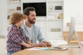 Man working remotely at home. Father and his son at desk with computer Royalty Free Stock Photo