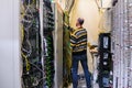 The man is working in the server room of the data center. The engineer connects the wires to provide Internet communication. The