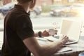 Man working at sunny office on laptop while sitting in cafe having coffee. Concept of young business people working in public spac Royalty Free Stock Photo