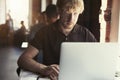 Man working at sunny office on laptop while sitting in cafe having coffee. Concept of young business people working in public spac Royalty Free Stock Photo