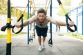 Man during workout with suspension straps on the street