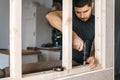 The man works as a screwdriver, fixing a wooden frame for the window to the gypsum plasterboard partition. Royalty Free Stock Photo