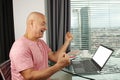 Man works behind a laptop with blank screen in an office in front of a window in a modern European city, the concept of business Royalty Free Stock Photo