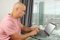 Man works behind a laptop with blank screen in an office in front of a window in a modern European city, the concept of business Royalty Free Stock Photo