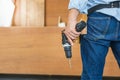 Man works in carpentry workshop. Handyman manual worker in tools belt and holding drill in his hands Royalty Free Stock Photo