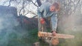 Man works in country house. Harvesting firewood in cottage of smoke background