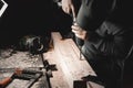 A man works with a drill in his workshop. Carpenter drills with a hand power tool in a dark room