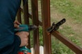 The man works in the garden. Construction tool in hands, screwdriver, close-up. Outdoor work