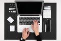 A man works with laptop, calculator, pens, pencils, card, phone on his desktop isolated on balck background