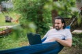 A man works with a laptop in a hammock in a country house Royalty Free Stock Photo