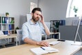 The man works in the office, the patient has a severe headache, upset businessman sitting at the table, holding his hands behind Royalty Free Stock Photo