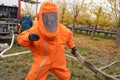 A man works in an orange chemical protection suit.