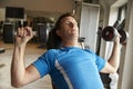 Man works out with dumbbells on a bench at a gym, front view Royalty Free Stock Photo