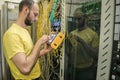 The man works in the server room of the datacenter. A technician measures the signal level in a fiber optic cable. The system Royalty Free Stock Photo