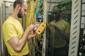 The man works in the server room of the datacenter. A technician measures the signal level in a fiber optic cable. The system