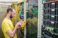 The man works in the server room of the datacenter. A technician measures the signal level in a fiber optic cable. The system