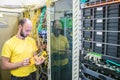 The man works in the server room of the datacenter. A technician measures the signal level in a fiber optic cable. The system Royalty Free Stock Photo