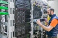 A man works in a server room. System administrator installs a new server in a modern data center. The engineer replaces the