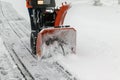 A man works with a snow blower to remove freshly fallen snow from a high voltage transformer driveway Royalty Free Stock Photo