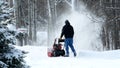 Man works with a snow blower to remove newly fallen snow from driveway Royalty Free Stock Photo