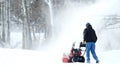 Man works with a snow blower to remove newly fallen snow from driveway Royalty Free Stock Photo