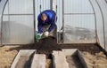 A man works in a vegetable garden in early spring. Digs the ground. Working in a greenhouse